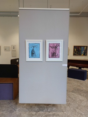 Das Bild zeigt Fotografien von Werken der Künstlerin Heike Pander in der Ausstellung "Druckkunst24 - Limited Edition" im Haus Mattéy in Aachen. Zu sehen sind zwei Monotypien mit Affenbrotbäumen, gerahmt, an einer grauen Tafel im Raum frei schwebend aufgehängt. Diese Gemeinschaftsausstellung wurde vom BBK Aachen/Euregio und dem BBK Bonn, Rhein-Sieg organisiert.