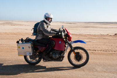 Das Bild zeigt das Foto von Matthias Kuhlmann auf dem Motorrad, unterwegs auf der Salzpiste an der Sekelton Coast in Namibia. Das Foto wurde von der Künstlerin Heike Pander während einer mehrmonatigen Motorradreise aufgenommen. 